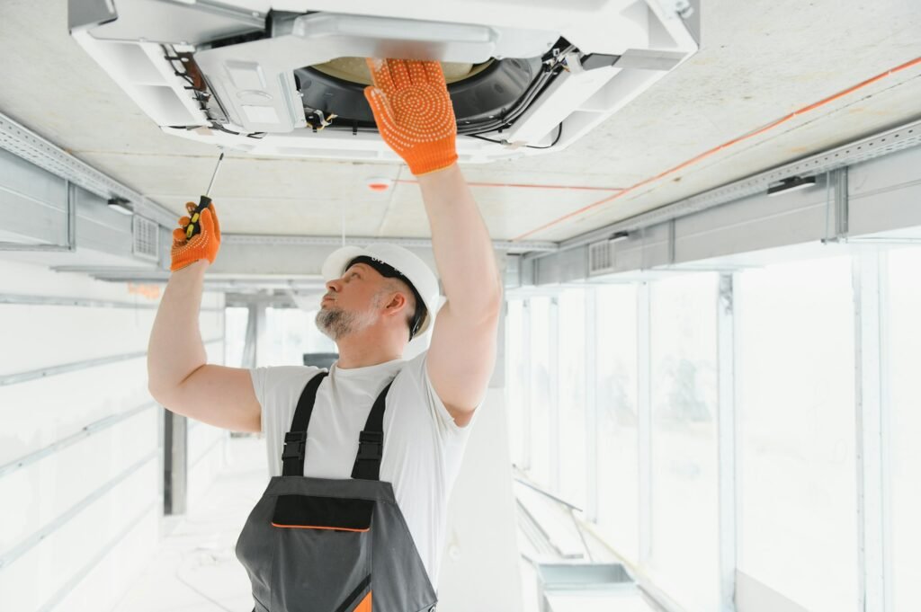 Worker repairing ceiling air conditioning unit