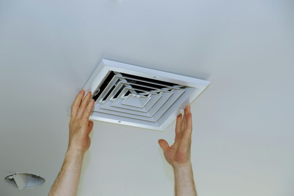 Close up man hand installing vent cover from ceiling Mounted Air Conditioner.